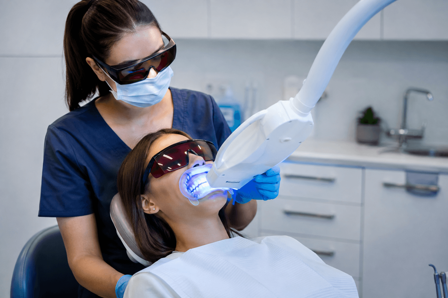 Professional teeth whitening treatment in progress with patient wearing protective glasses